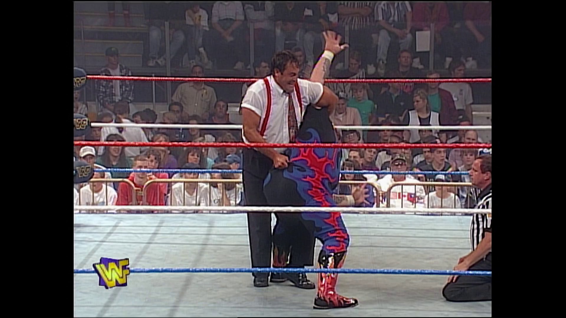 A frame from WWE Raw (May 15, 1995) at 42:33. # WWE Raw Wrestling Match

A wrestler in white shirt and red/blue patterned pants celebrates in the ring with his fist raised, while an opponent lies on the mat. The crowd fills the arena seats behind the red and blue ropes, with the WWF logo visible in the corner.