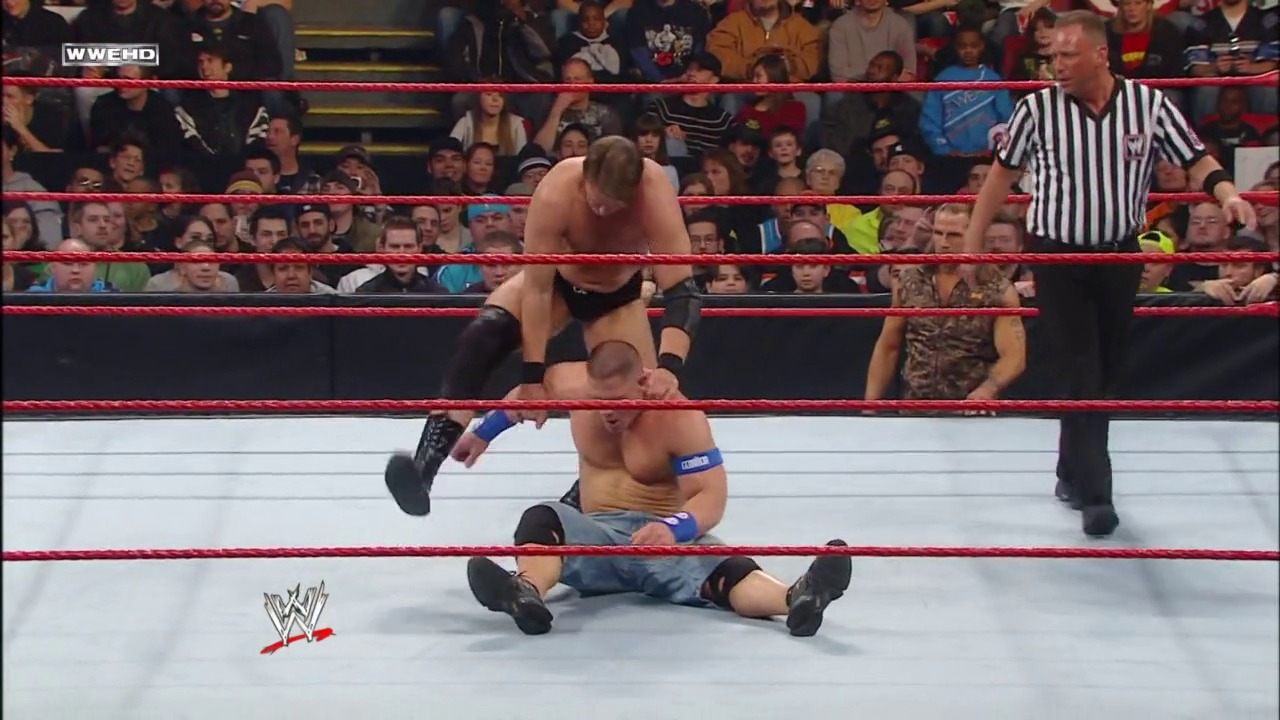 A frame from WWE Royal Rumble (2009) at 46:45. # WWE Royal Rumble 2009 Match

A wrestler in black attire dominates an opponent in blue wristbands on the mat, while a referee in striped shirt oversees the action. The packed crowd surrounds the red-roped ring, with the WWE logo visible on the canvas.