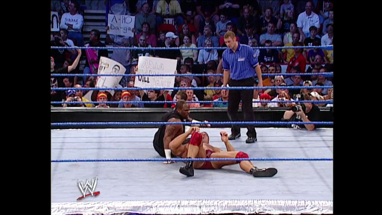 A frame from WWE Raw (September 5, 2002) at 49:41. A WWE wrestler lies on the mat after taking a move during a match, while the referee stands nearby and the crowd watches from the stands. The blue-roped ring and WWE logo are visible in this professional wrestling broadcast frame.