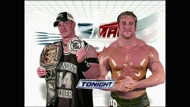 A frame from WWE SmackDown (April 29, 2005) at 25:00. Two wrestlers pose together for the camera during WWE SmackDown. The wrestler on the left wears a cap and holds a championship belt, while the shirtless wrestler on the right displays his physique, with "TONIGHT" graphics and branding visible in the background.
