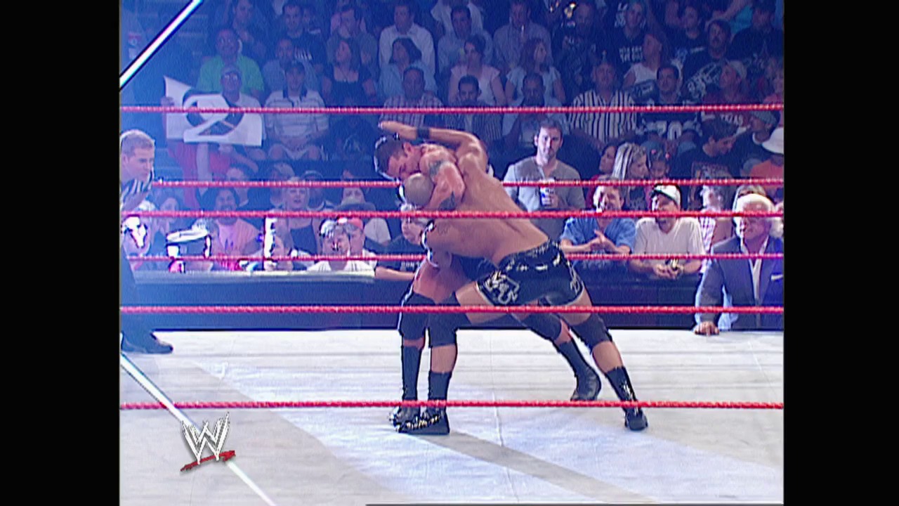 A frame from WWE Raw (June 16, 2003) at 1:08:19. Two wrestlers grapple in a WWE Raw match inside a ring with red ropes, while a crowd watches from the stands behind them. The WWE logo appears in the bottom left corner of the broadcast.