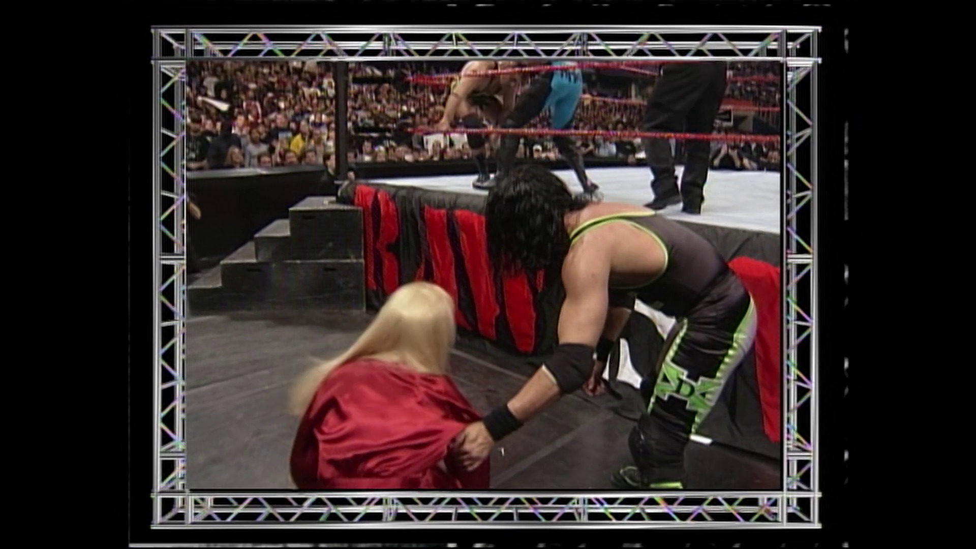 A frame from WWE Raw (March 1, 1999) at 41:38. # WWE Raw Match Scene

A wrestler in black and neon green attire dominates the ring against an opponent in red, while the crowd fills the arena stands. The distinctive red WWE ring ropes and packed audience are visible in the background of this intense in-ring action.