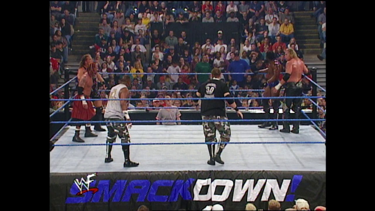 A frame from WWE SmackDown (October 25, 2001) at 25:59. A WWE SmackDown wrestling match in progress with multiple wrestlers in and around the ring, surrounded by an energetic crowd. The blue-roped ring and "SmackDown" logo are prominently displayed at the bottom of the broadcast footage.