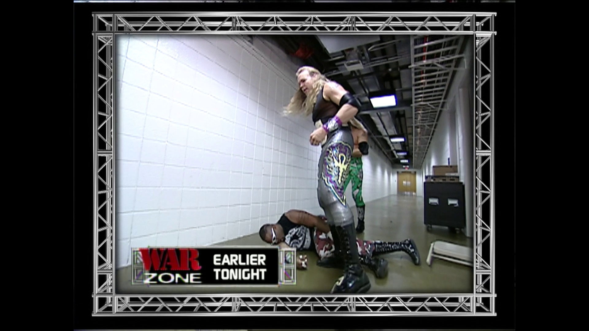 A frame from WWE Raw (January 15, 2001) at 1:24:25. A WWE wrestler performs a move on an opponent in a backstage corridor with white tiled walls. The "War Zone" graphic and "Earlier Tonight" text appear in the lower left corner of the broadcast frame.