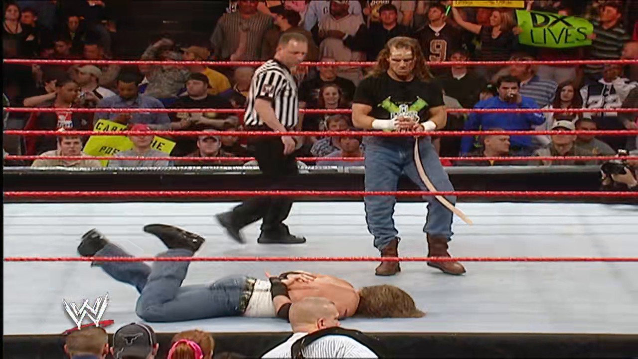 A frame from WWE Raw (January 22, 2007) at 1:18:56. A WWE wrestler lies on the mat while another stands nearby in the ring, with a referee in a striped shirt overseeing the match. The crowd fills the arena behind the red ropes, and the WWE logo is visible in the lower left corner.