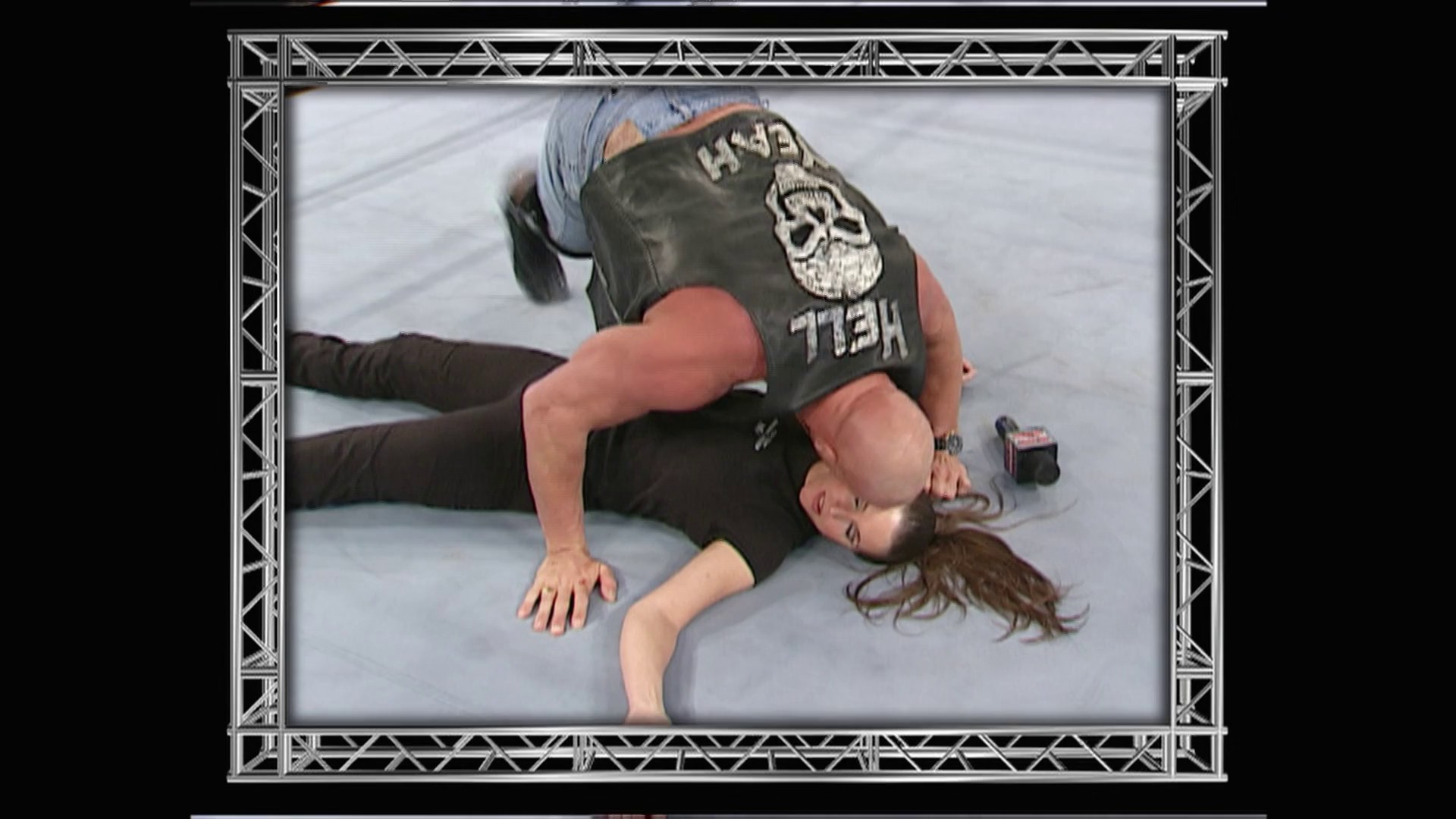 A frame from WWE Raw (February 19, 2001) at 50:09. # Visual Description

A wrestler lies on the mat in the WWE ring wearing a dark shirt with graphic design. The frame is bordered by an ornate metal truss-style frame, typical of WWE broadcast graphics from this era.