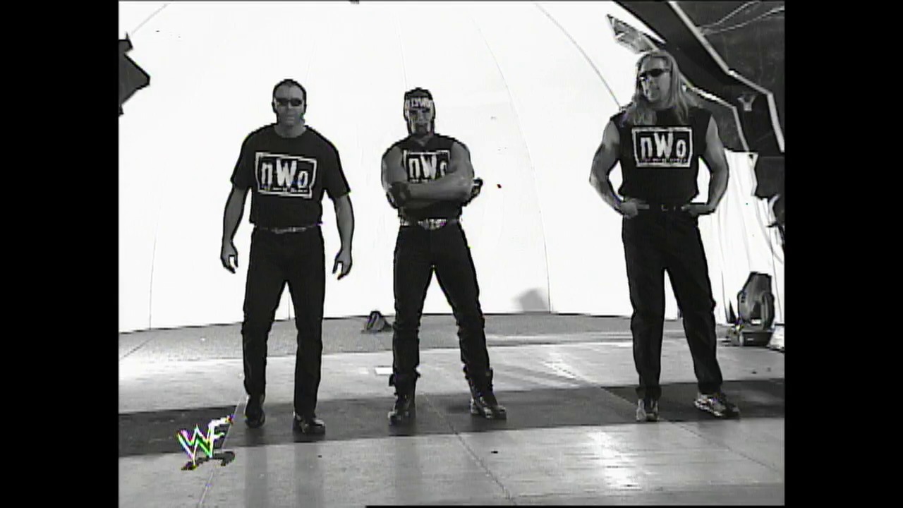 A frame from WWE Raw (February 28, 2002) at 12:55. Three wrestlers wearing nWo (New World Order) black shirts stand in a wrestling ring under bright lighting, with the WWF logo visible in the corner of the frame.