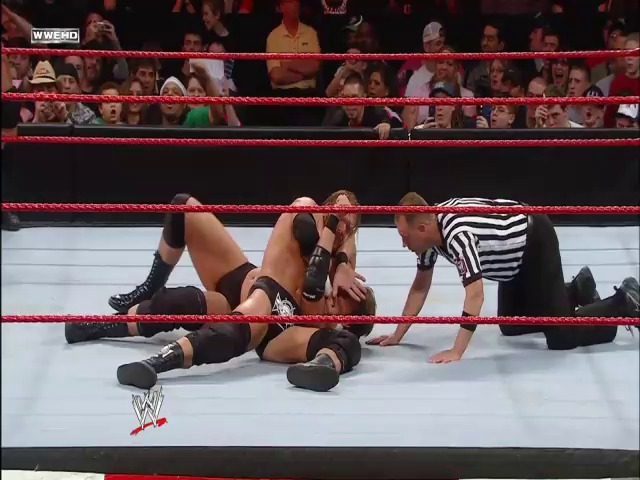 A frame from WWE Raw (April 7, 2008) at 38:15. A WWE wrestler lies on the mat during a match as a referee in a striped shirt checks on them, with the red ropes and enthusiastic crowd visible in the background at a WWE Raw event.