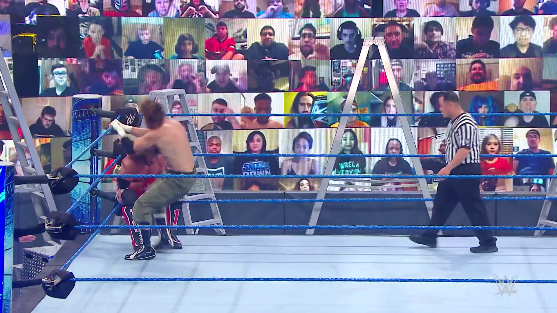 A frame from WWE SmackDown (September 25, 2020) at 12:55. A WWE wrestler performs in the ring during a match broadcast from an empty arena, with the audience displayed on screens behind the ring. A referee in a striped shirt officiates the action on the blue-roped wrestling ring.