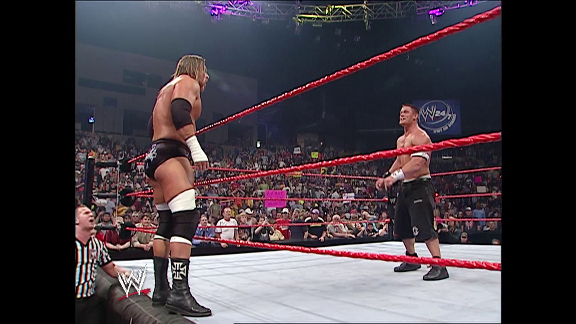 A frame from WWE Raw (March 13, 2006) at 1:35:01. Two wrestlers face off in a WWE RAW ring with red ropes, surrounded by a roaring crowd. A referee stands nearby as the shirtless competitors prepare for combat in this professional wrestling match.