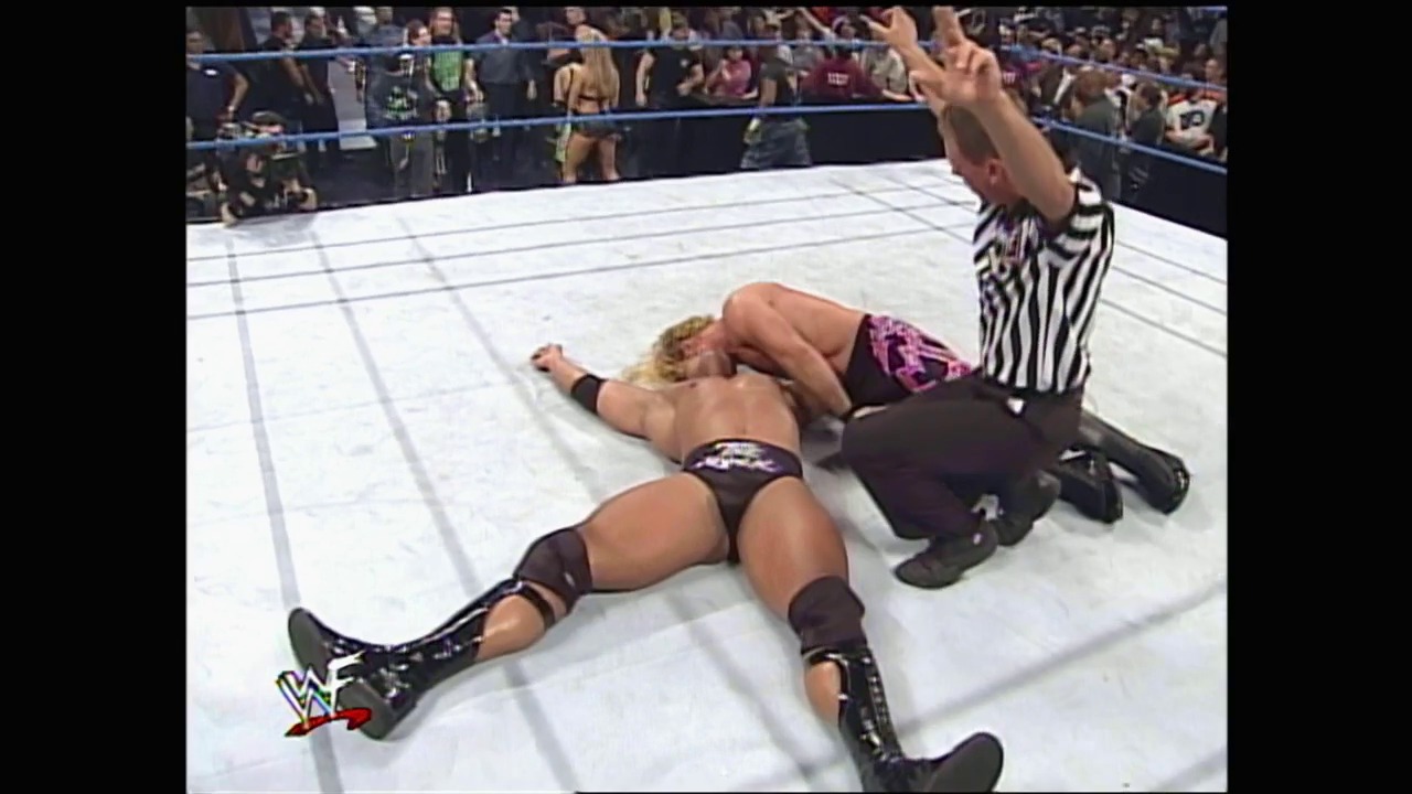 A frame from WWE SmackDown (April 20, 2000) at 1:28:40. A wrestler lies pinned on the white WWE ring mat while a referee in striped shirt signals the match outcome, with a packed crowd visible behind the blue ropes in the background.