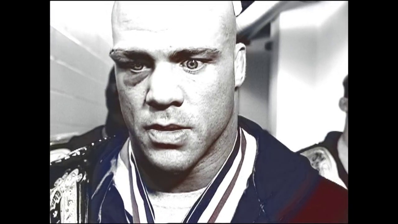 A frame from WrestleMania XIX (2003) at 3:13:40. A close-up shot of a bald male wrestler in a dark jacket with ornate embroidery, displaying an intense facial expression. The background shows blurred arena elements, characteristic of a professional wrestling broadcast.