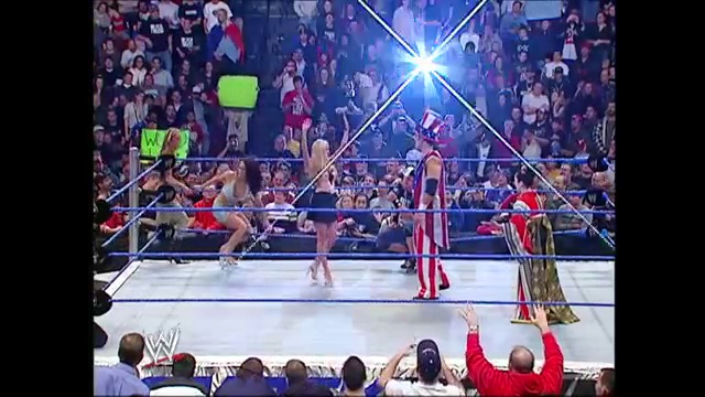 A frame from WWE SmackDown (January 6, 2005) at 48:41. A WWE wrestler in red and gold attire stands in the ring during a SmackDown event, with the crowd visible in the background and bright overhead lighting illuminating the wrestling arena.