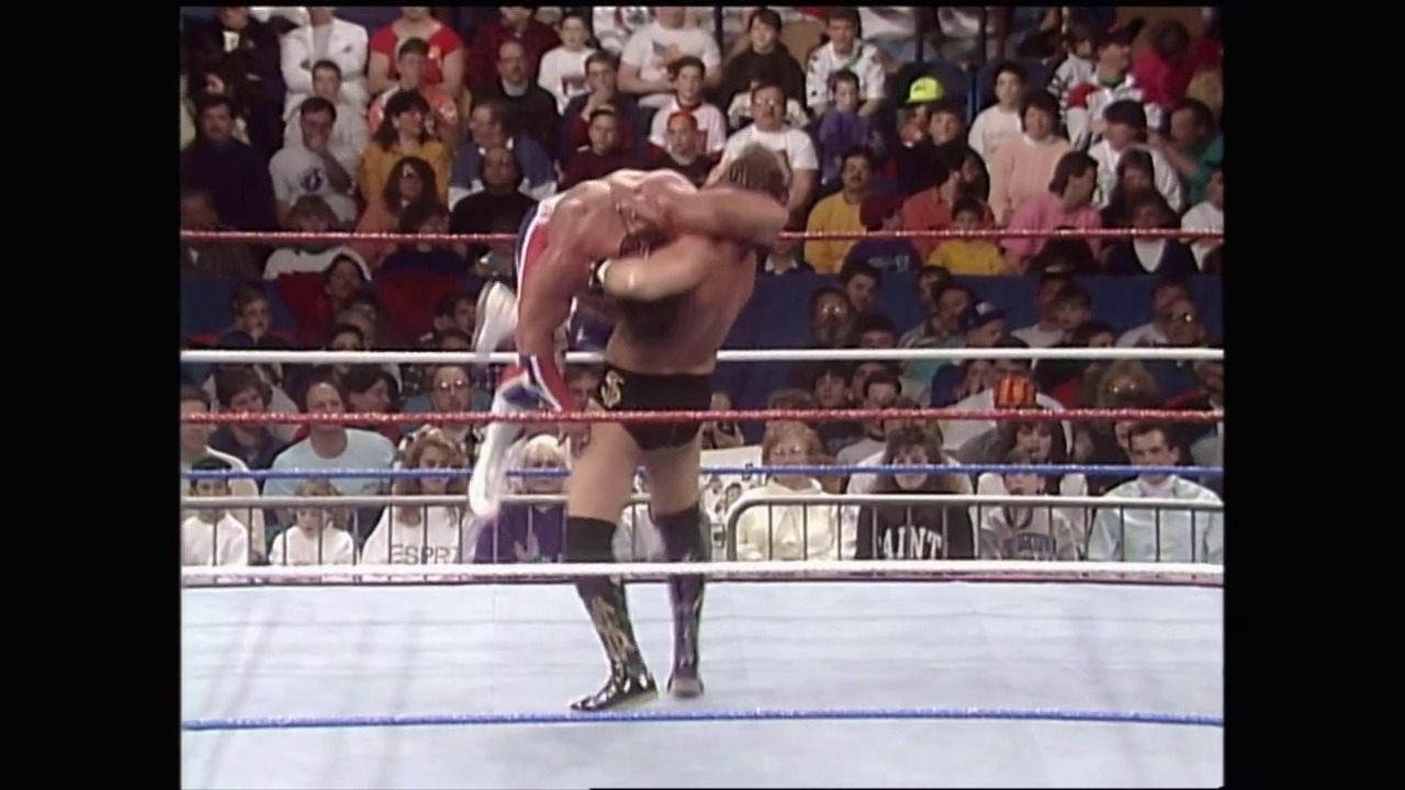 A frame from Royal Rumble (1992) at 1:31:22. A shirtless wrestler performs in a WWE ring during the 1992 Royal Rumble event, with a packed crowd of spectators visible in the background behind the ropes and barricades.