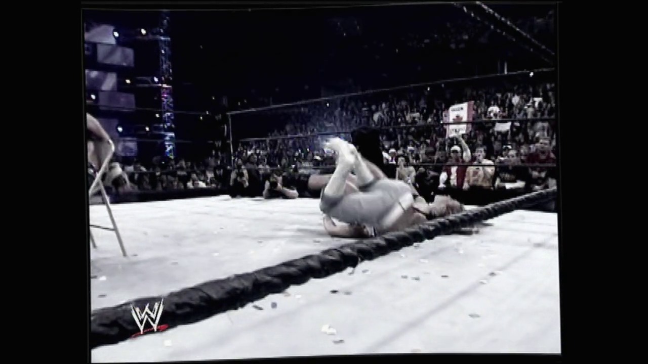 A frame from WrestleMania 22 (2006) at 1:39:41. A wrestler lies on their back on the mat after being thrown, while the crowd cheers in the background. The WWE logo is visible in the lower left corner of the broadcast.
