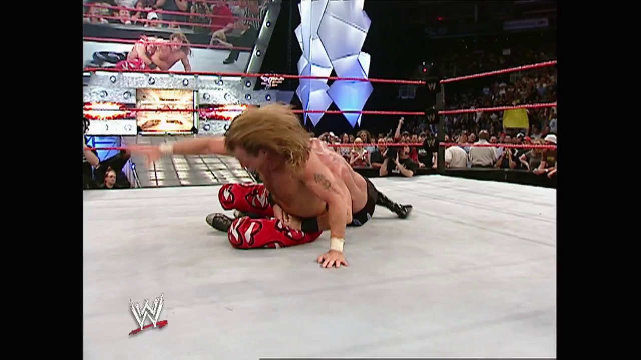 A frame from WWE Raw (May 3, 2004) at 1:20:59. A WWE wrestler in red and black attire performs in the ring during Raw, with the crowd visible in the background and the WWE logo displayed at the bottom of the screen.