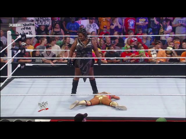 A frame from WWE Raw (May 9, 2011) at 25:27. A WWE wrestler in black attire stands over a fallen opponent lying on the white ring canvas during a Raw match, with an enthusiastic crowd visible in the background behind the ropes.