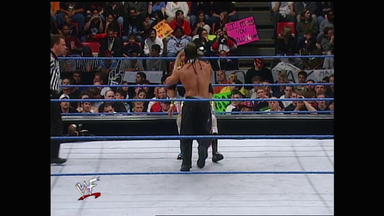 A frame from WWE SmackDown (May 18, 2000) at 37:20. A shirtless wrestler stands in a WWE ring with blue ropes, facing an enthusiastic crowd holding signs. The WWF logo is visible on the canvas as fans cheer from the stands around the ring.