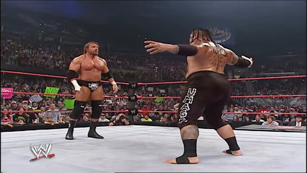 A frame from WWE Raw (October 1, 2007) at 48:06. Two shirtless wrestlers face off in a WWE ring, with one assuming an aggressive stance while the other observes from across the mat. A packed crowd fills the arena seats behind the red ropes as the WWE logo appears in the lower left corner.