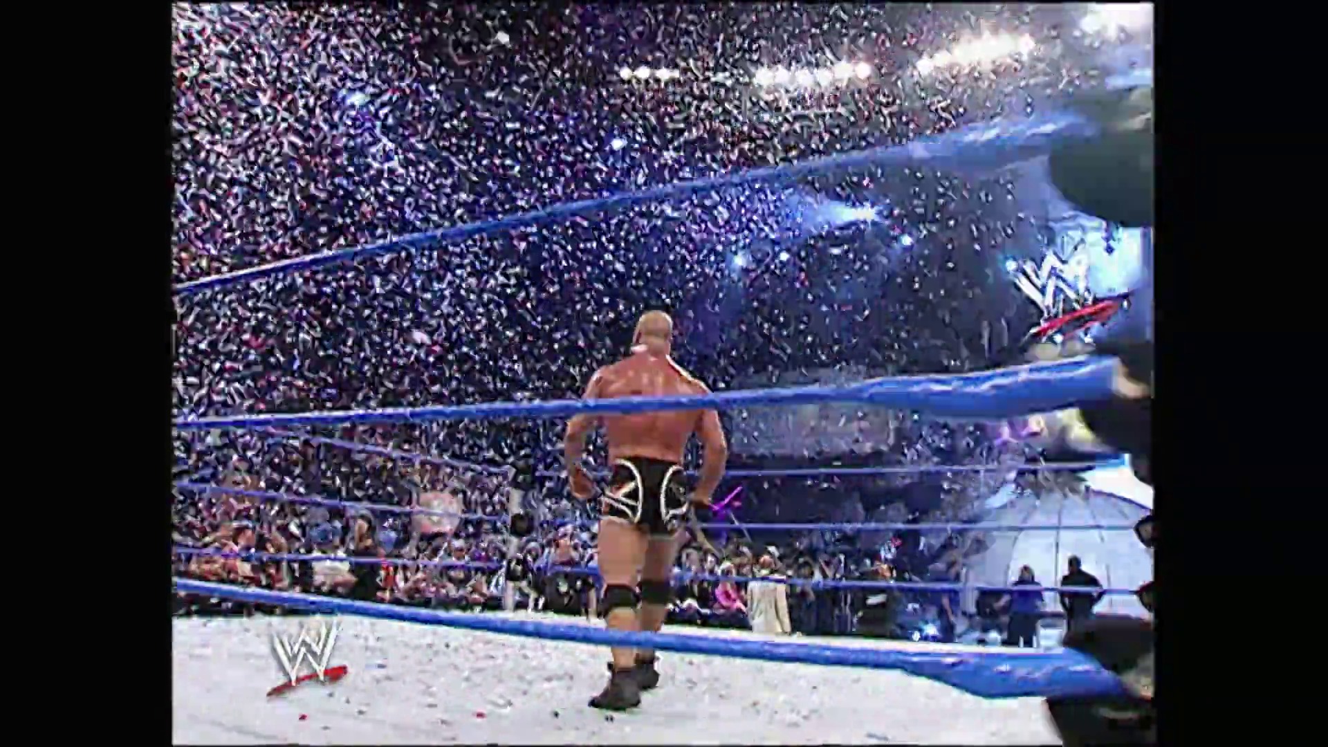 A frame from WWE SmackDown (January 13, 2006) at 1:28:35. A shirtless wrestler stands in a WWE SmackDown ring surrounded by a massive cheering crowd, with confetti falling from above and the blue-roped ring prominently featured in the foreground.