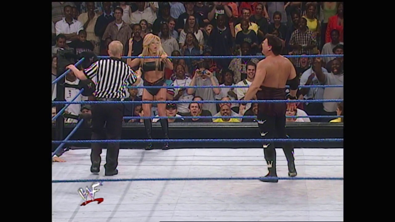 A frame from WWE SmackDown (June 22, 2000) at 1:03:36. A WWE SmackDown match features a female wrestler in the ring with a male opponent and referee, surrounded by a crowd and blue-roped ring. The WWF logo is visible in the lower left corner.