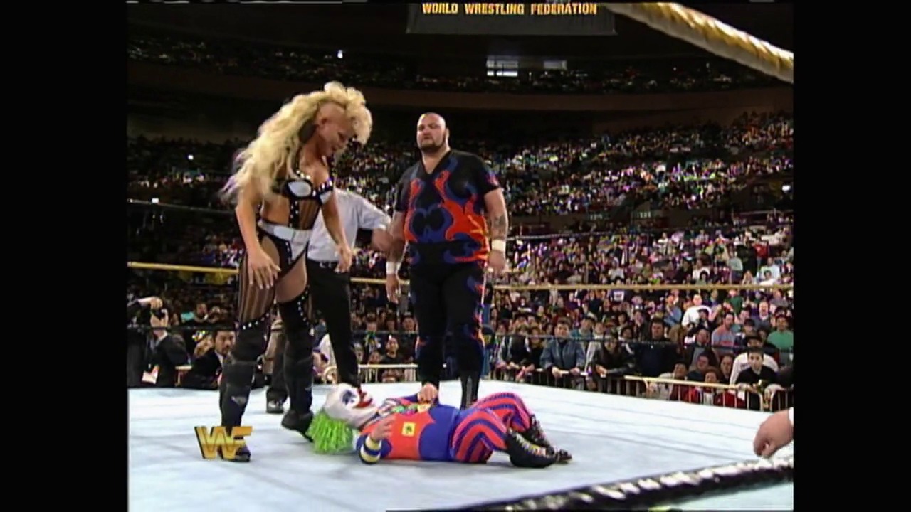 A frame from WrestleMania X (1994) at 47:02. # WrestleMania X (1994) - Visual Description

Two wrestlers stand in the WWF ring while a fallen opponent lies on the mat, with a packed stadium crowd visible in the background and the "WORLD WRESTLING FEDERATION" banner displayed above.