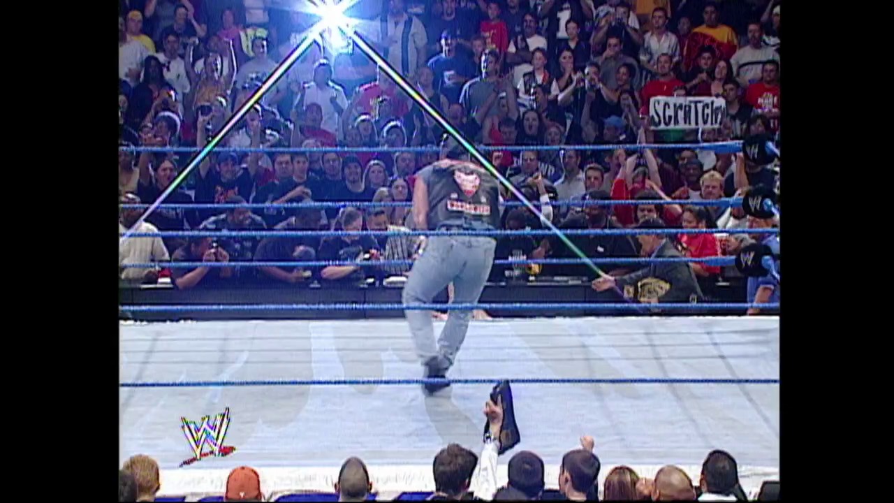 A frame from WWE Raw (October 10, 2002) at 1:22:17. A WWE wrestler stands in the illuminated blue wrestling ring during Raw, with a massive crowd visible in the bleachers behind the ropes. The iconic WWE logo is displayed in the lower left corner of the broadcast.