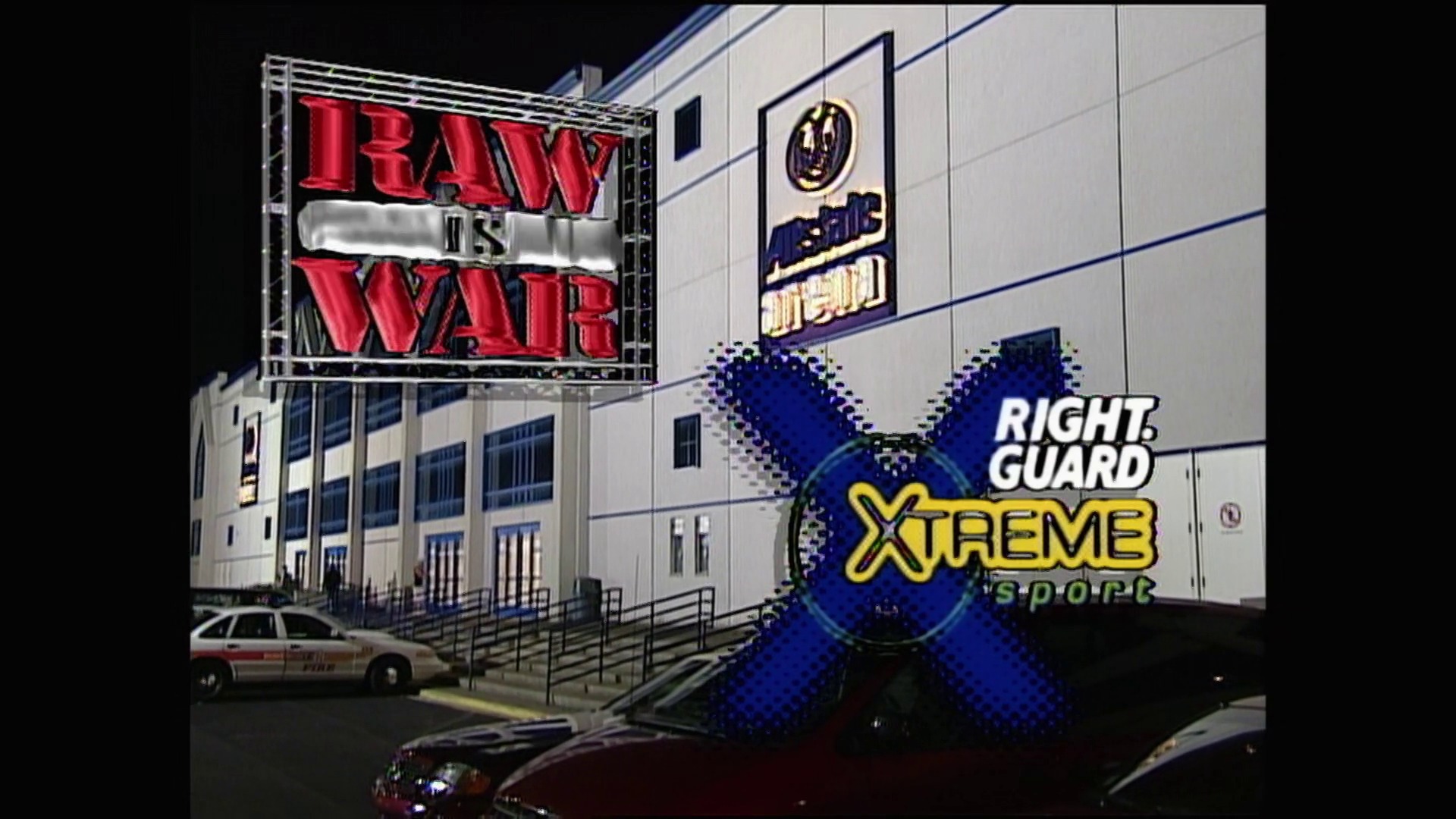 A frame from WWE Raw (September 18, 2000) at 1:05:02. # WWE Raw September 18, 2000

A large arena exterior displays a "RAW IS WAR" neon sign, with a blue X-shaped graphic promoting "Right Guard Xtreme Sport" overlaid on the building facade, featuring police vehicles and the venue entrance.
