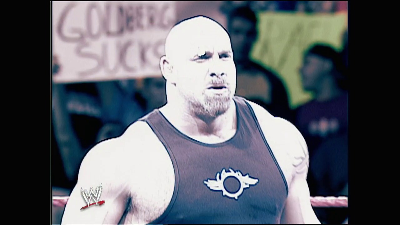 A frame from WWE Unforgiven (2003) at 2:21:15. # WWE Unforgiven (2003) Frame

A muscular bald wrestler with a goatee stands in the ring wearing a dark tank top with a sun logo, with the WWE logo visible in the corner and spectators blurred in the background.